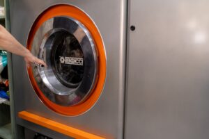lavandería con autoservicio en Valencia - mano en la lavadora
